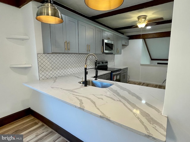 kitchen featuring wood finished floors, a sink, appliances with stainless steel finishes, and backsplash
