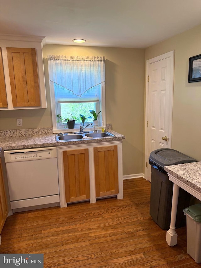 kitchen with light countertops, white dishwasher, a sink, and wood finished floors