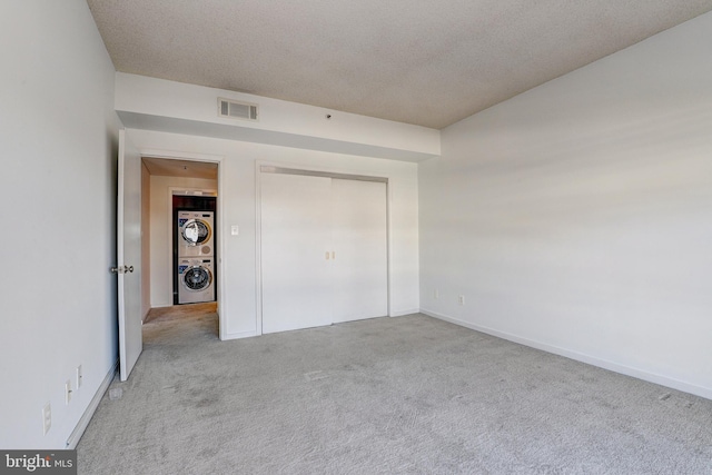 250 President St Unit 308, Baltimore, MD 21202 - unfurnished bedroom with a textured ceiling, stacked washer / dryer, visible vents, baseboards, and carpet