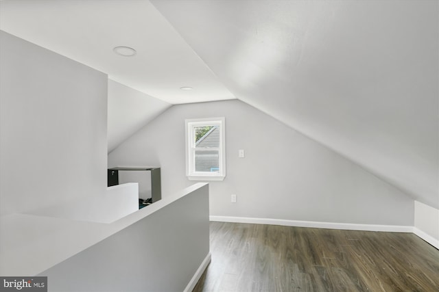 additional living space featuring baseboards, wood finished floors, and vaulted ceiling