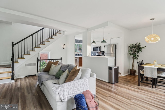 1240 Martha Custis Dr, Alexandria, VA 22302 - living room with radiator, wood finished floors, stairs, and baseboards