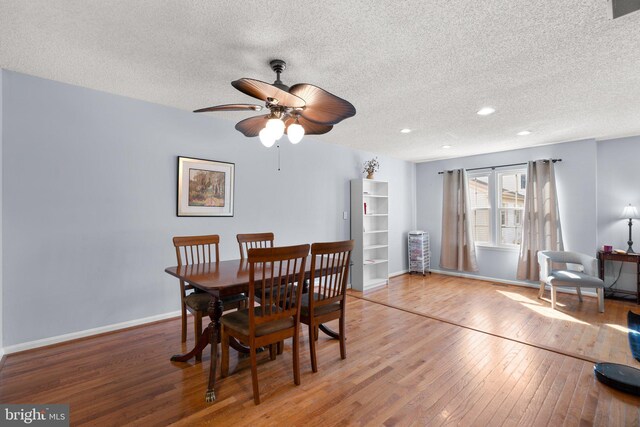 dining space featuring baseboards, light wood-style flooring, a textured ceiling, and a ceiling fan