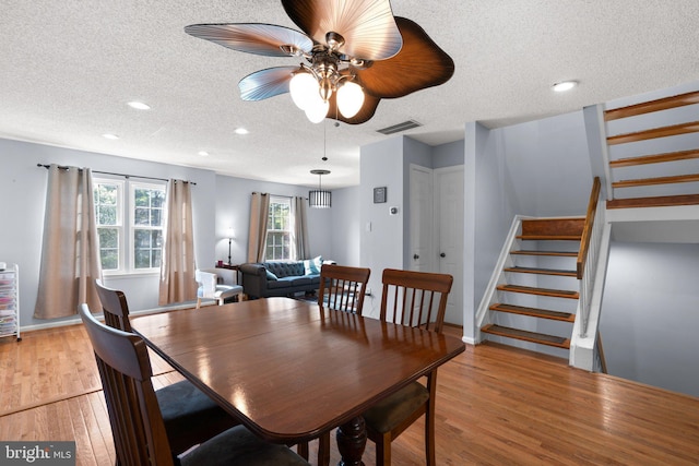 dining room featuring visible vents, a textured ceiling, stairs, and a ceiling fan