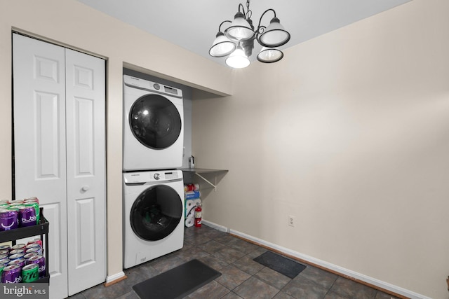 washroom featuring laundry area, baseboards, stacked washer / drying machine, and a notable chandelier