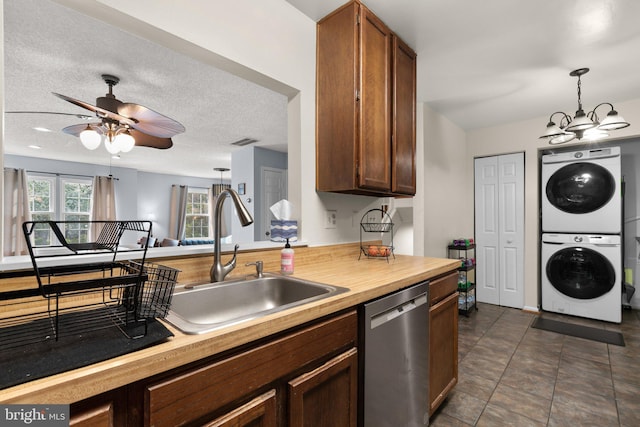 kitchen with a sink, stacked washing maching and dryer, ceiling fan with notable chandelier, stainless steel dishwasher, and visible vents