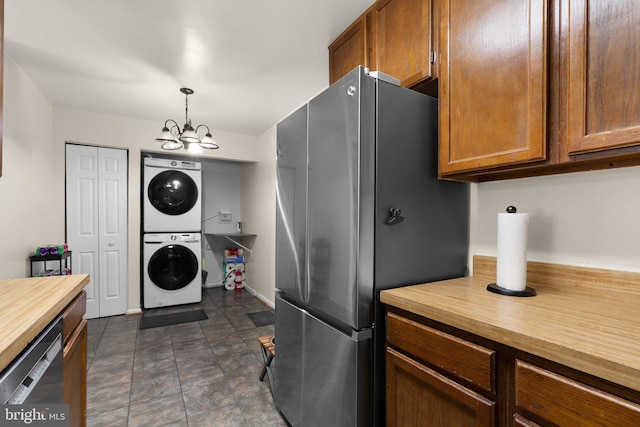 kitchen featuring brown cabinets, stacked washing maching and dryer, butcher block counters, an inviting chandelier, and stainless steel appliances