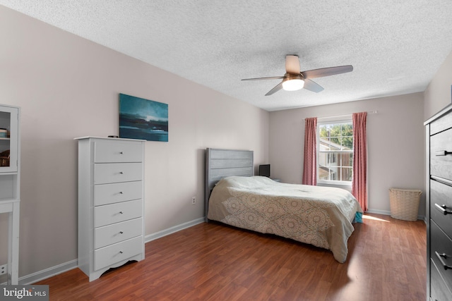 bedroom with baseboards, a ceiling fan, a textured ceiling, and wood finished floors