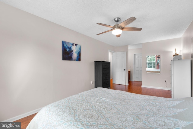 bedroom featuring baseboards, a ceiling fan, a textured ceiling, and wood finished floors