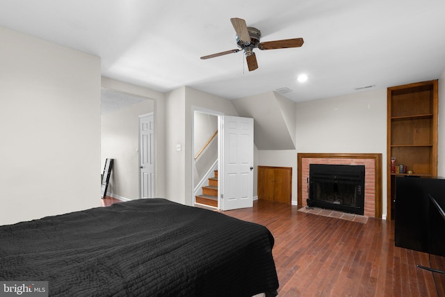 bedroom with baseboards, a brick fireplace, wood finished floors, and visible vents