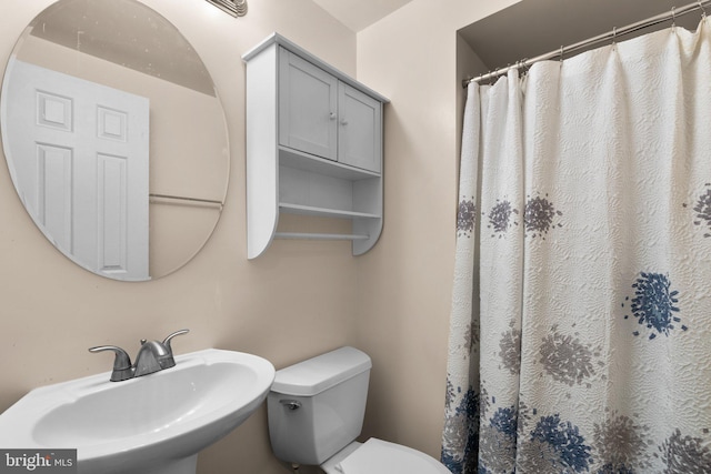 bathroom featuring a sink, toilet, and a shower with shower curtain