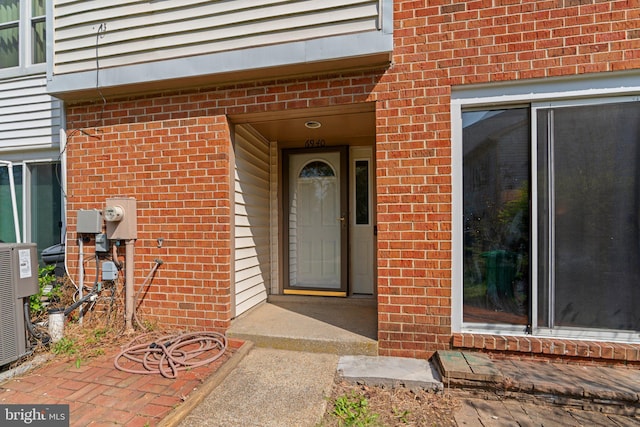 property entrance with brick siding and central AC unit