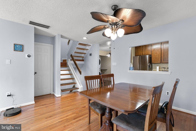 dining room with visible vents, baseboards, ceiling fan, stairway, and light wood finished floors