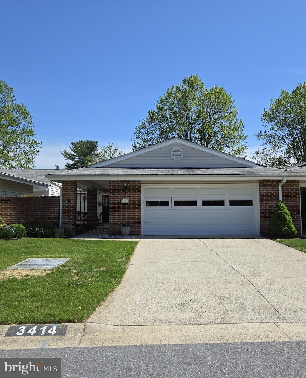 single story home featuring driveway, a garage, a front yard, and brick siding