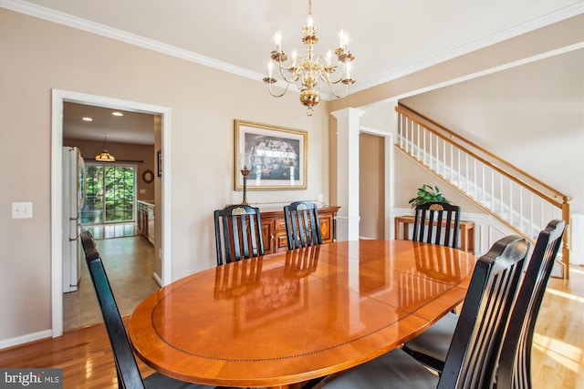 dining area with crown molding, a notable chandelier, stairs, baseboards, and wood finished floors
