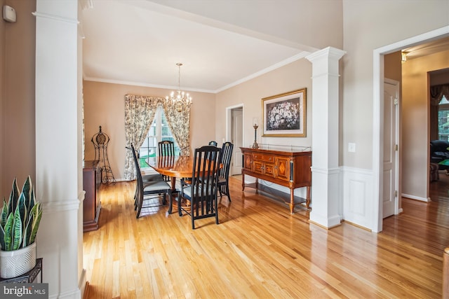 dining room featuring an inviting chandelier, ornamental molding, decorative columns, and light wood finished floors