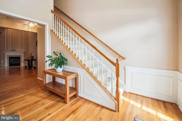 stairway featuring wainscoting, a decorative wall, and wood finished floors
