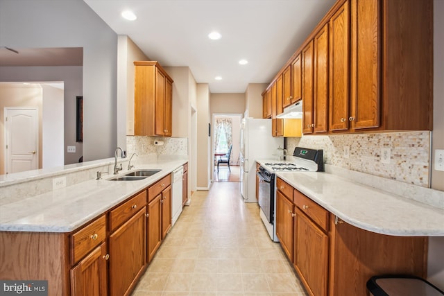 kitchen with white dishwasher, a sink, a peninsula, gas range, and backsplash