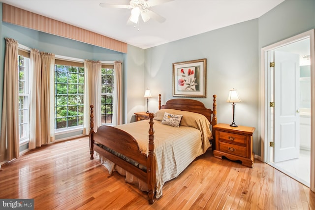 bedroom with connected bathroom, a ceiling fan, and light wood finished floors