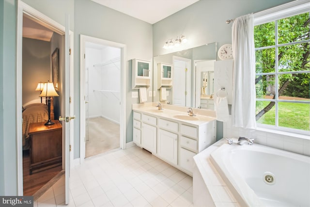 bathroom featuring double vanity, a whirlpool tub, tile patterned floors, and a sink