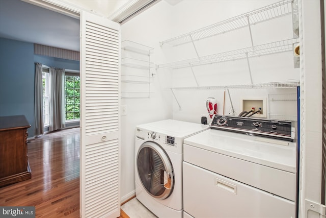 clothes washing area with laundry area, washer and dryer, and light wood-type flooring