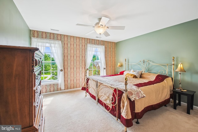 carpeted bedroom featuring baseboards, a ceiling fan, wallpapered walls, and visible vents