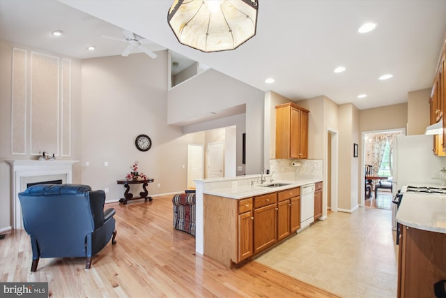 kitchen featuring brown cabinets, white dishwasher, a sink, light countertops, and backsplash