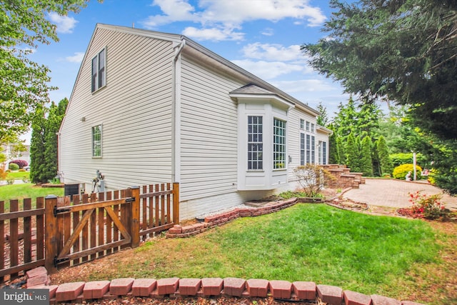 view of home's exterior featuring a lawn, fence, and a patio area