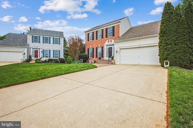 colonial inspired home with a garage, a shingled roof, driveway, and a front yard