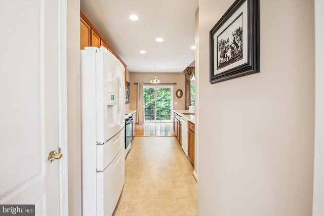 kitchen with recessed lighting, light countertops, brown cabinetry, and white appliances