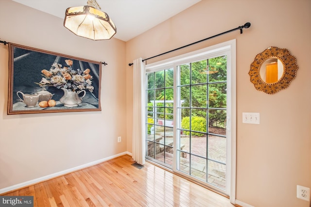 doorway to outside with baseboards, visible vents, and wood finished floors