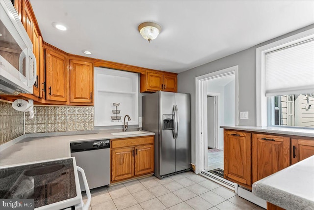kitchen featuring light countertops, brown cabinets, a sink, appliances with stainless steel finishes, and backsplash