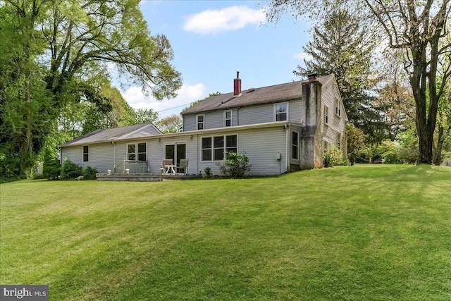 rear view of property featuring a lawn, a chimney, and a deck