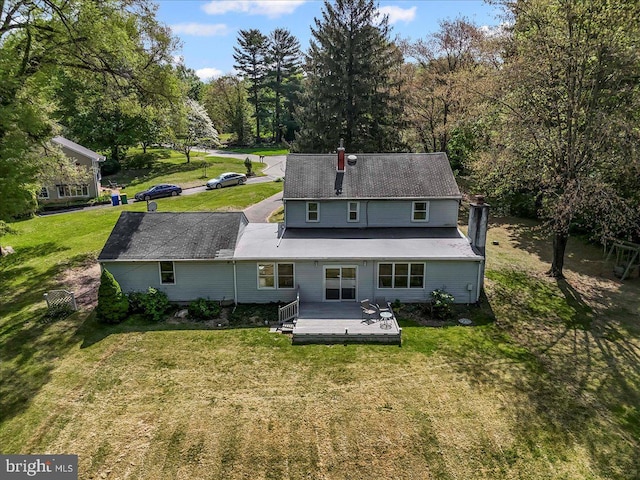 rear view of house featuring a wooden deck, a yard, and a chimney