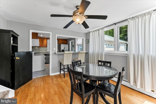dining room featuring baseboards, light wood finished floors, ceiling fan, and baseboard heating