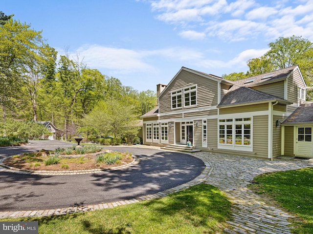 view of front facade featuring a chimney and a shingled roof