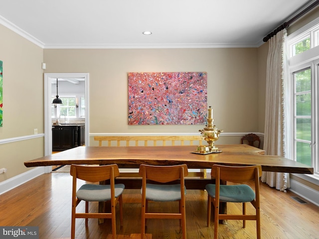 dining space with baseboards, ornamental molding, light wood-style flooring, and visible vents