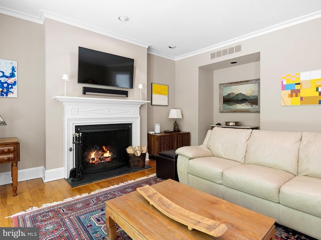 living room with baseboards, visible vents, ornamental molding, and wood finished floors