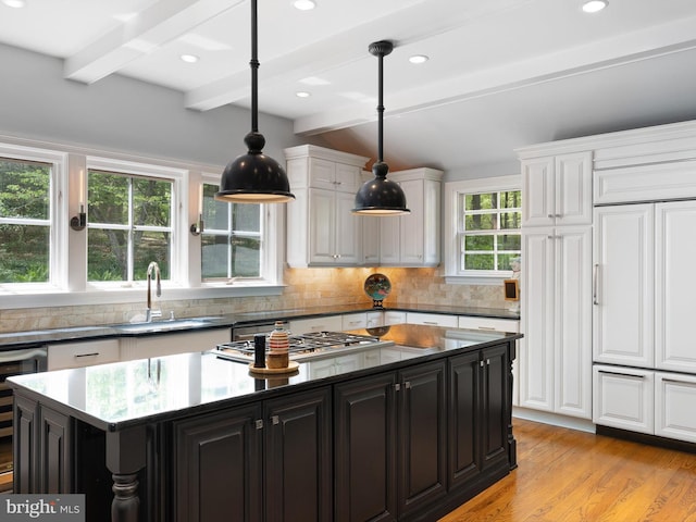 kitchen with beamed ceiling, white cabinetry, dark cabinetry, a sink, and stainless steel gas stovetop