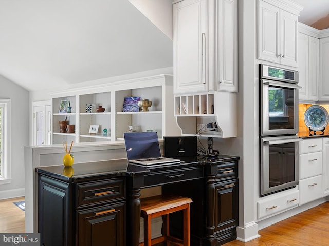 kitchen featuring dark countertops, open shelves, light wood-type flooring, double oven, and white cabinetry