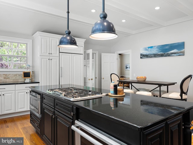 kitchen with stainless steel gas stovetop, a center island, white cabinets, and light wood finished floors