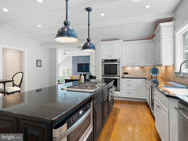 kitchen featuring beam ceiling, light wood-type flooring, white cabinetry, a sink, and appliances with stainless steel finishes