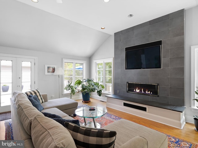 living room with lofted ceiling, wood finished floors, a fireplace, recessed lighting, and french doors