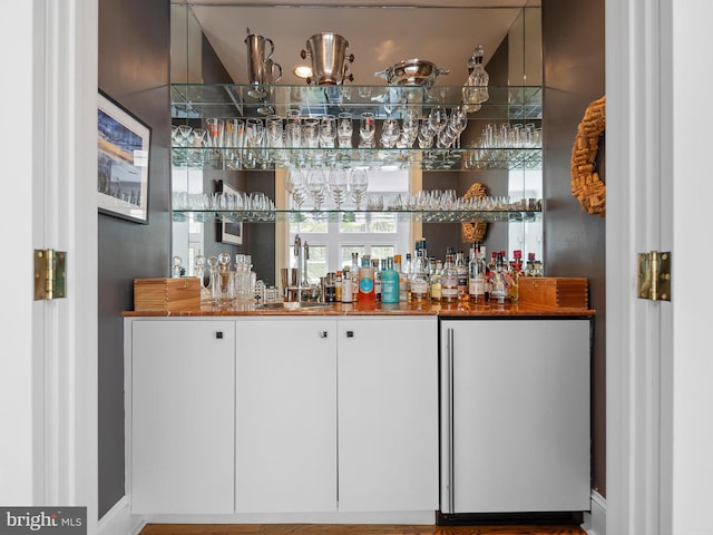 bar with indoor wet bar, baseboards, a chandelier, and a sink