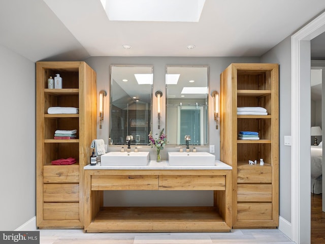 bathroom with double vanity, a sink, wood finished floors, and a shower stall