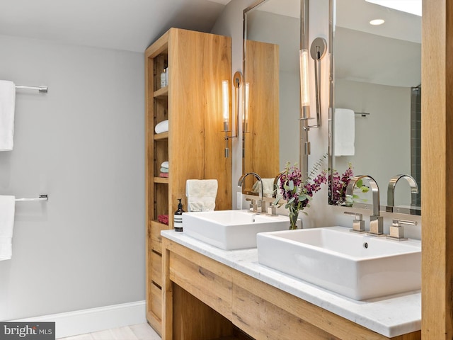full bath featuring double vanity, baseboards, and a sink