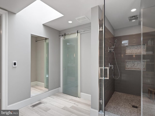 bathroom featuring visible vents, wood finished floors, baseboards, recessed lighting, and a stall shower
