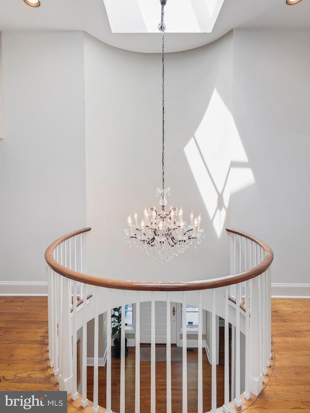 interior space featuring a skylight, baseboards, wood finished floors, and a notable chandelier