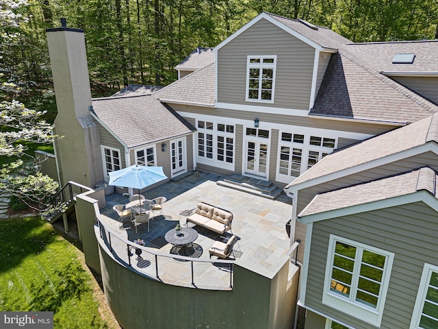 rear view of property with a patio, a shingled roof, french doors, and an outdoor hangout area