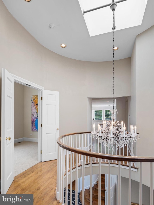 hallway with a notable chandelier, light wood-style flooring, recessed lighting, baseboards, and a skylight