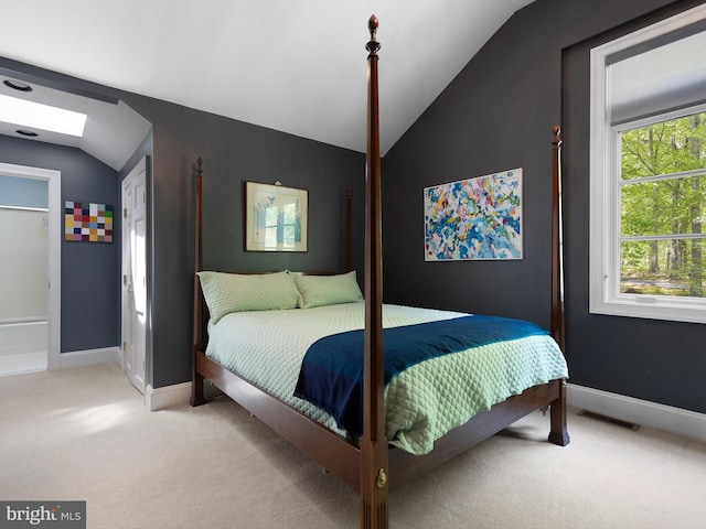 bedroom with baseboards, visible vents, light carpet, and vaulted ceiling with skylight